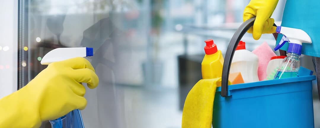 Two people with rubber gloves on holding cleaning products and washing a window